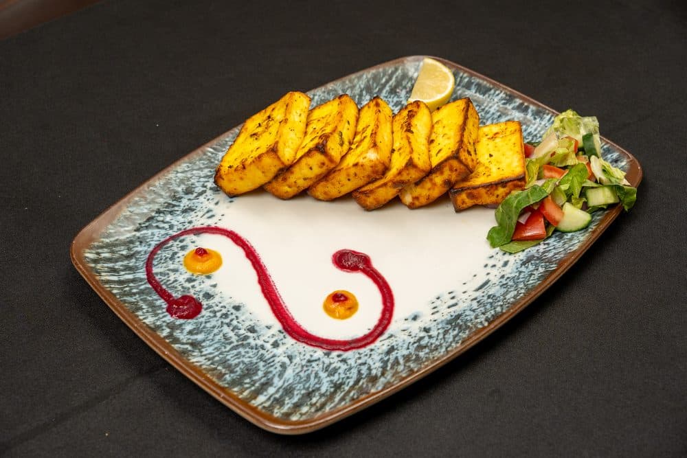 Grilled paneer tikka slices with a side salad and dipping sauces